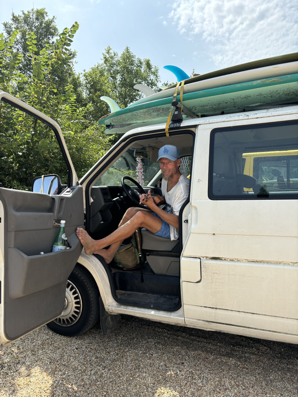 Surfakademiens Jens Holmer med en ukulele på armen og surfebrett på taket.