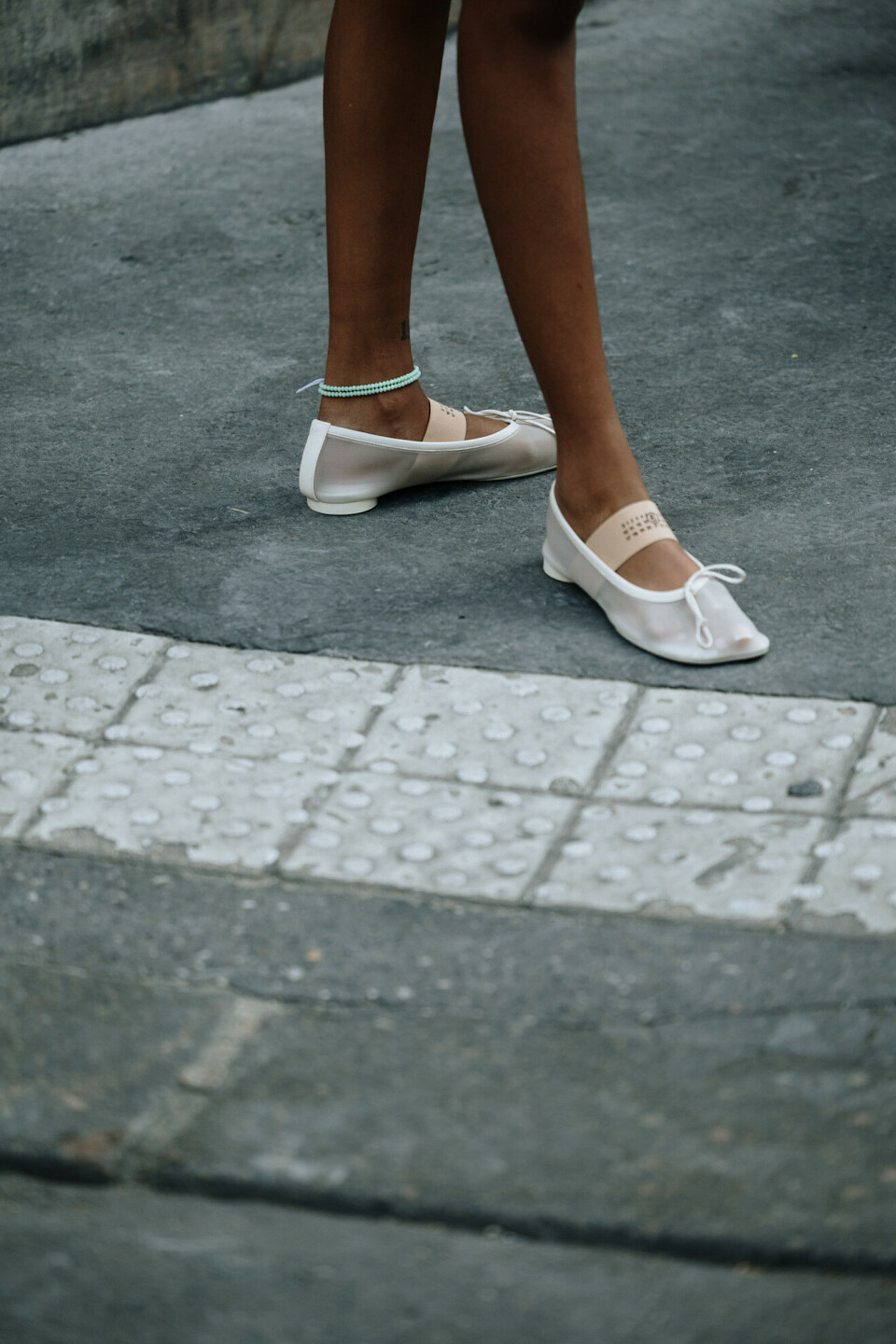 Den turkise ankelkjeden gir et friskt blikkfang mot de ellers minimalistiske ballerinaskoene – enig? Bildet er hentet fra Paris street style under menswear-uken SS26.
