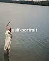 Modell i hvit kjole fra self‑portrait står og poserer i grunt innsjøvann