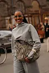 Kvinne i grått antrekk med stor sebramønstret veske.