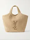 Beige Saint Laurent-tote i fuskepels med gyllent YSL-monogram mot lys bakgrunn.