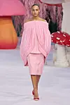 Modell i rosa kjole går på catwalk omgitt av store fargerike soppscenografier.