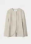 Beige minimalistisk jakke uten synlige knapper mot lys bakgrunn.