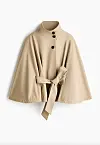Beige kåpecape med knytebelte og høyt halsparti hengende mot hvit bakgrunn.