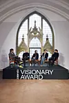 Panel med fem personer på Zalando Visionary Award-scene foran stor buet vindusvegg.