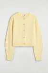 Smørgul, cropped cardigan med knapper lagt flatt mot lys bakgrunn.