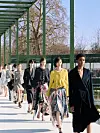 Modeller i Dior-antrekk går på utendørs catwalk ved en dam omgitt av grønne konstruksjoner.