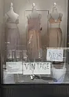 Utstillingsvindu med tre kjoler på hvite mannequiner og skilt som viser vintage og Dior.