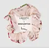 Blomstrete rosa scrunchie fra Liberty Fabrics & Bridgerton by Bondep mot lys bakgrunn.