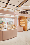 Lys butikkinnredning med CAIA-logo, produkter i hyller og sminkedisplay i en moderne shop-in-shop.