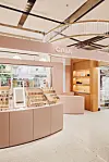 Lys butikkinnredning med CAIA-logo, produkter i hyller og sminkedisplay i en moderne shop-in-shop.