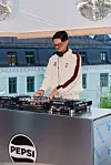 En DJ står bak et Pioneer-anlegg og mikser musikk under et telt med speilkuler.