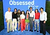 A group of cast members pose in front of an Obsessed Fest backdrop at a Prime Video event in Los Angeles.