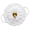 Hvitt, blomsterformet serveringsfat fra Le Creuset med gullfarget knapp i midten og håndtak på sidene.