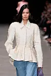 En modell går på catwalken for Stella McCartney i en paljettjakke og blå jeans under en motevisning.