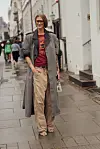 Marianne Theodorsen poserer i et lag-på-lag-antrekk med beige bukser, grå kåpe, sportstrøye og store solbriller under Copenhagen Fashion Week i København.