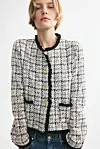 En modell viser en rutete bouclejakke fra H&M med svarte detaljer.