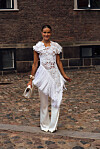 Nina Sandbech poserer i et hvitt, dekorativt antrekk med blonder, frynser og vide bukser under Copenhagen Fashion Week.