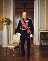 KONG HARALD V: Norges konge står i uniform i en rikt utsmykket sal, omgitt av kunstferdige detaljer og klassisk interiør.