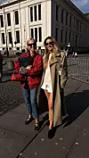 To kvinner i moderne antrekk står på fortauet foran en klassisk bygning i Oslo.