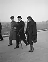 Svart-hvitt-foto av tre personer i mørke klær; kvinnen til høyre bærer hatt og sørgeslør.