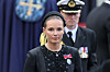 Kronprinsesse Ingrid Alexandra i svart antrekk med ordener, fotografert foran en uniformert vakt.