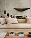 Lys stue med beige sofa, puter, veggdekor, salongbord og bøker.