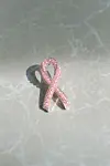 En rosa sløyfe dekorert med perler ligger på en lys, marmorert overflate.