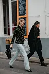 To kvinner går på en bygate; den ene bruker lyse jeans og den andre et mørkt antrekk.